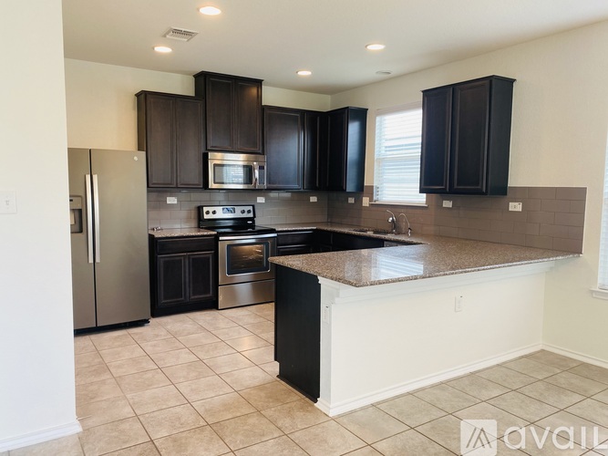 A kitchen with black cabinets and a stainless steel refrigerator.