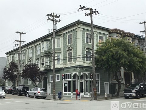 A street view of a green building with cars parked in front.