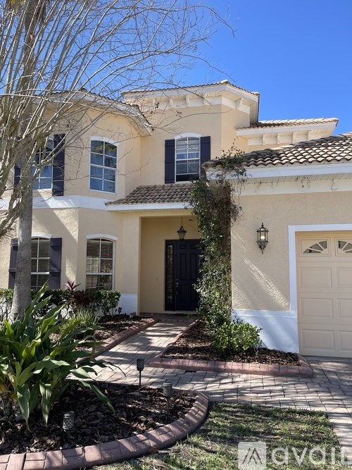 A beige house with a black door and a white garage door.