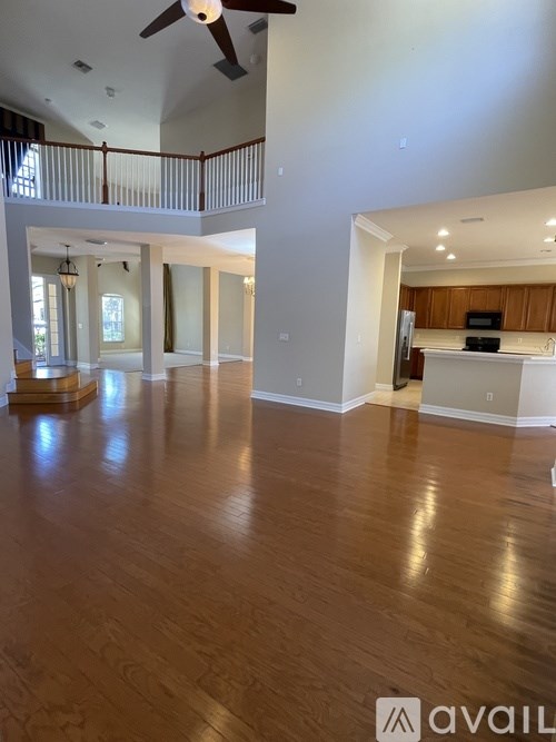A spacious room with wooden floors and a ceiling fan.