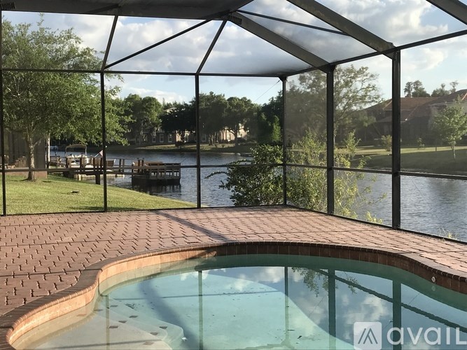 A pool under a glass roof with a view of a lake and trees.
