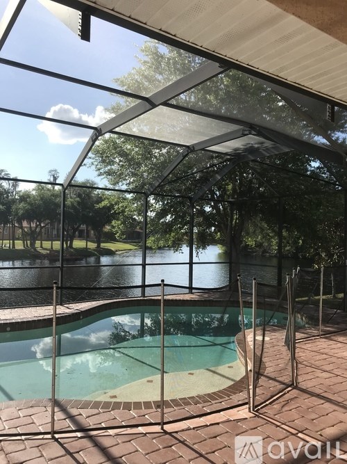 A pool enclosed by a glass wall with trees in the background.