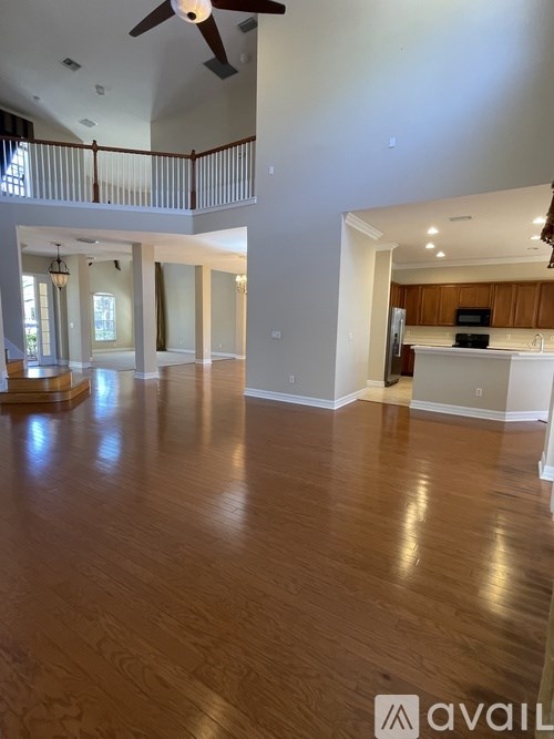 A spacious room with wooden floors and a ceiling fan.