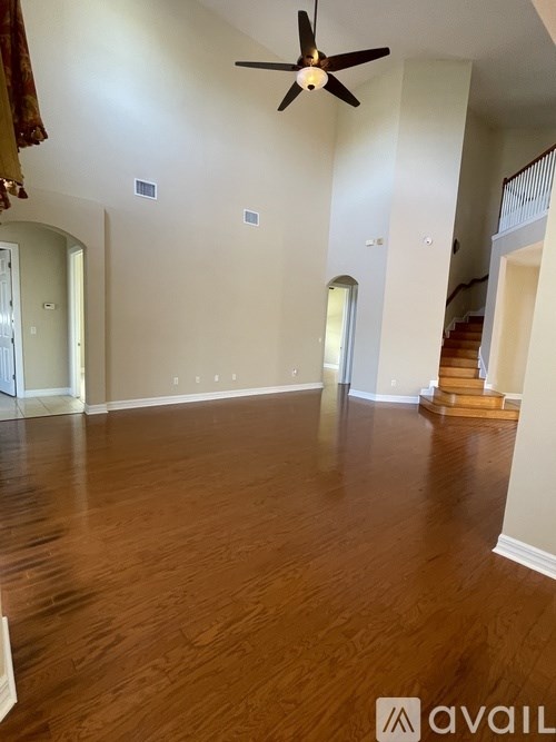 A spacious room with wooden floors and a ceiling fan.