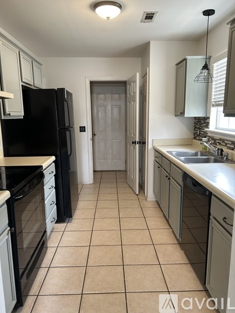 A kitchen with black appliances and white cabinets.