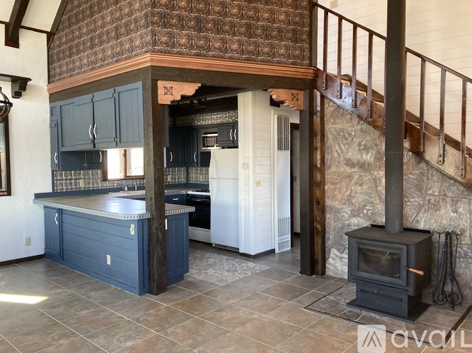 A wood stove is in a stone fireplace in a kitchen.