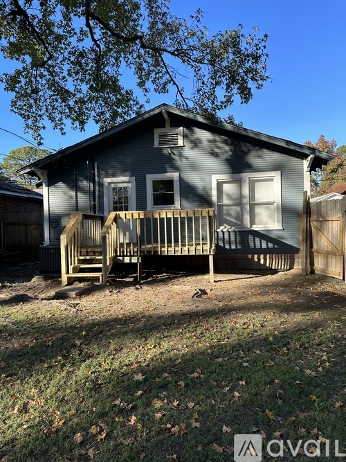 A house with a porch and a tree in front.