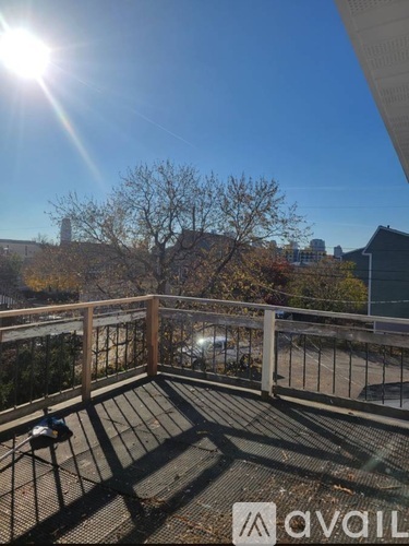 A balcony with a railing and a view of a parking lot and buildings.