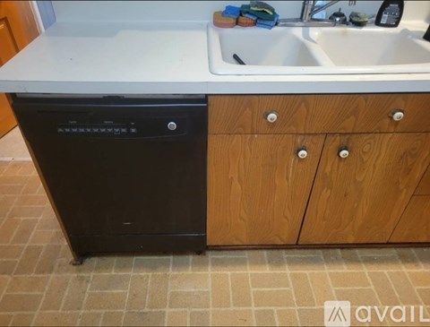 A black dishwasher is in a kitchen next to a sink.