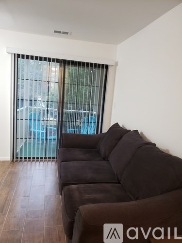 A living room with a brown couch and a sliding glass door.