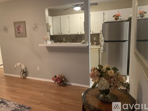 A kitchen with a refrigerator, a counter, and a table with flowers on it.
