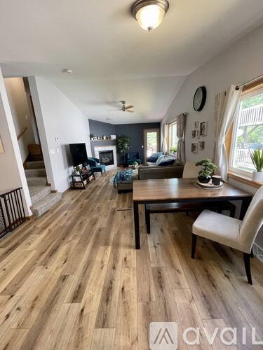 A living room with a wooden floor and a dining table with chairs.