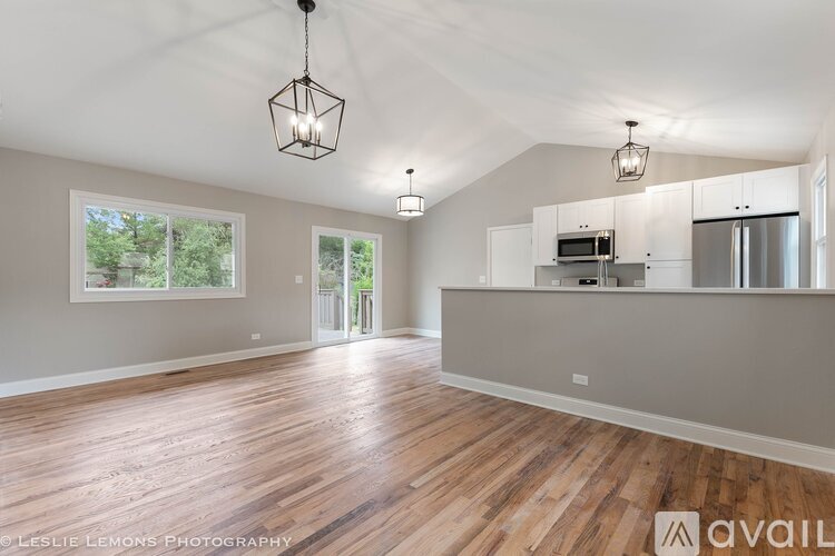 A spacious room with wooden floors and a kitchen area in the background.