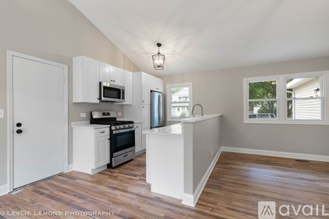 A kitchen with white cabinets and a wooden floor.