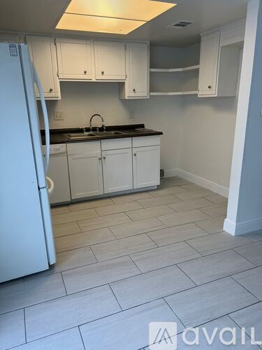 A kitchen with white cabinets and a white fridge.