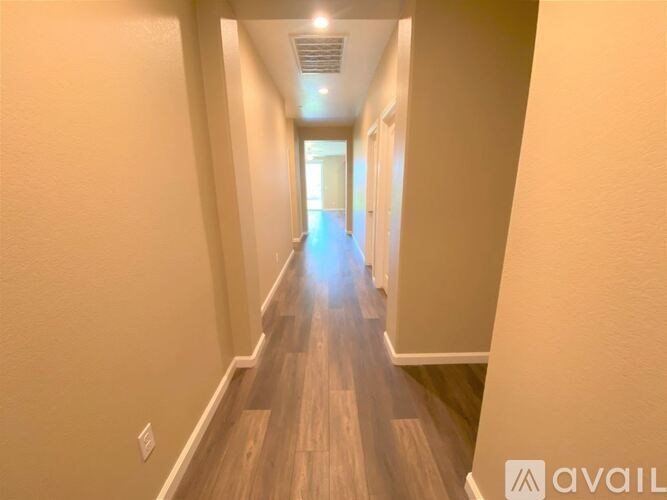 A long hallway with wooden floors and white walls.