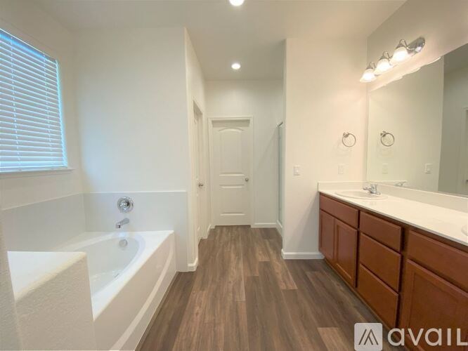 A bathroom with a white tub and brown flooring.