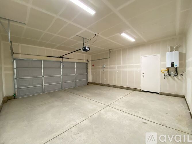 A spacious garage with a closed grey shutter door and a white door on the right side.