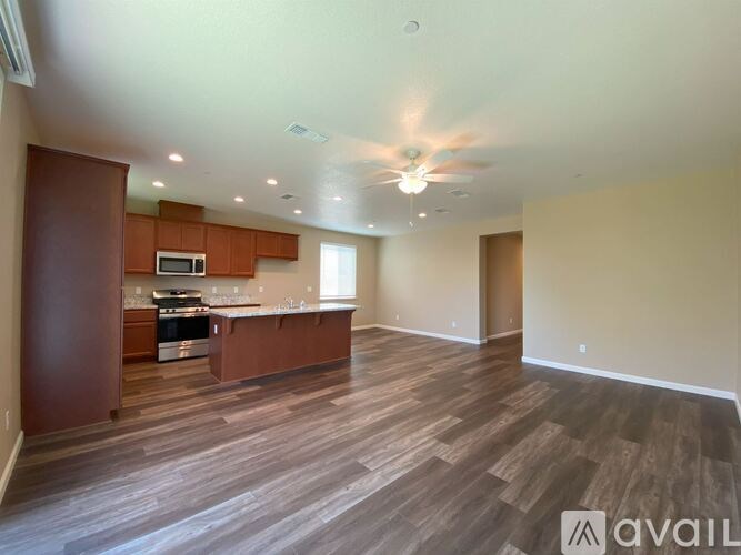 A spacious kitchen and living room with wood flooring and a ceiling fan.