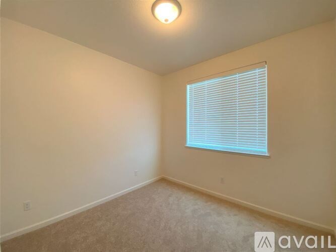 A room with a window covered by blinds and a light on the ceiling.