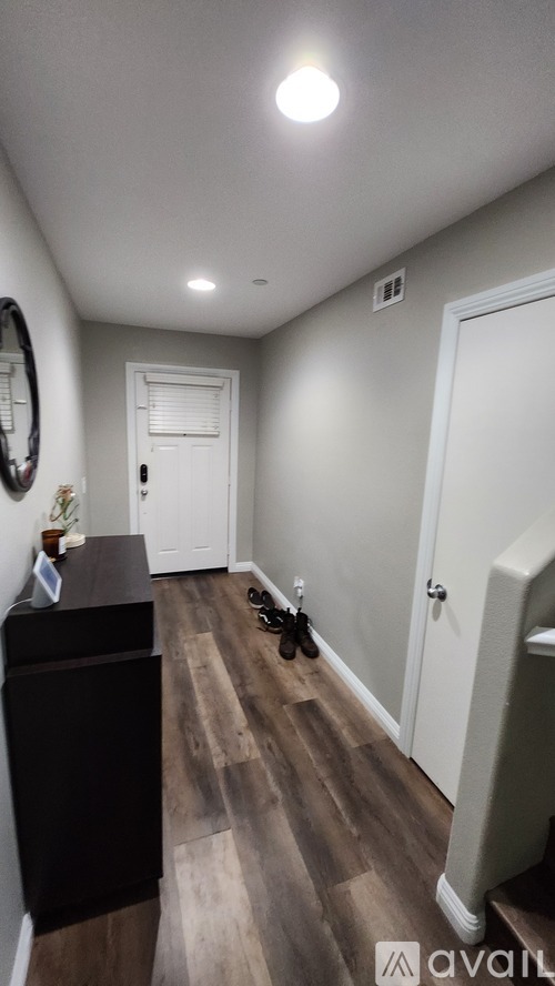 A hallway with a black cabinet and a pair of shoes on the floor.
