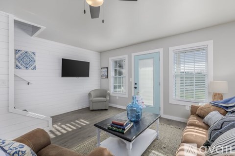 A living room with a brown couch and a blue vase on the coffee table.