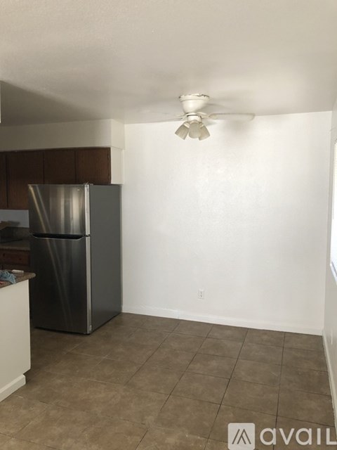 A kitchen with a refrigerator and a fan on the ceiling.