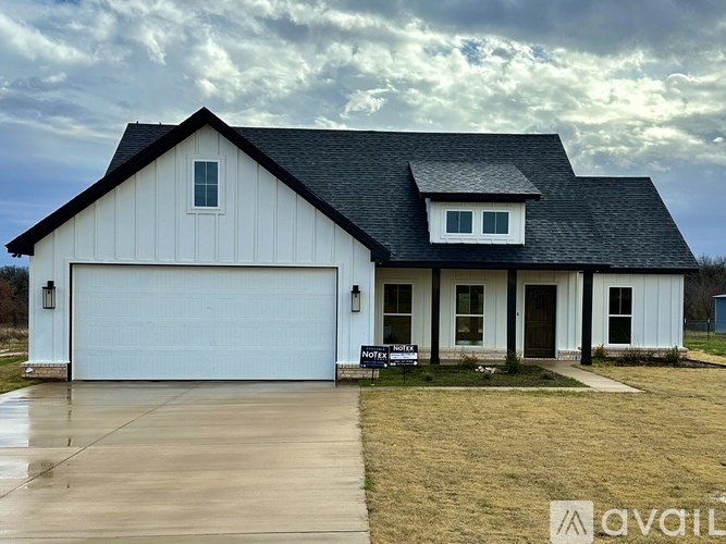 A white barn-style house with a black roof and a sign that says "NOTEBOOK".