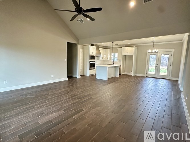 A spacious room with a ceiling fan and wooden flooring.