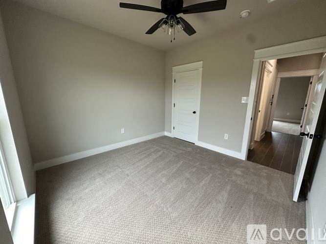 A room with a ceiling fan and carpeted floor.