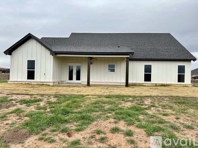 A white barn-style house with a black roof and a brown door.