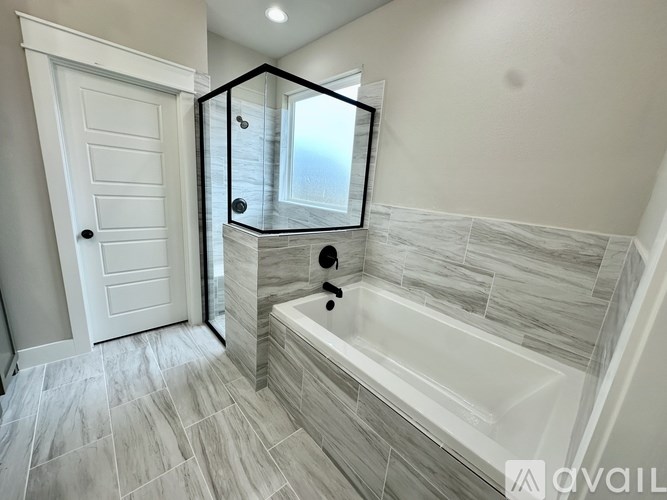 A bathroom with a white tub and grey tiles.