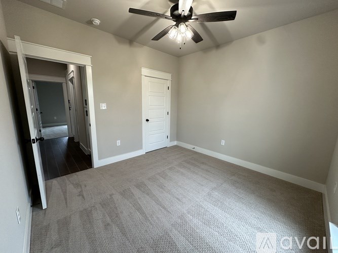 A room with a ceiling fan and carpeted floor.