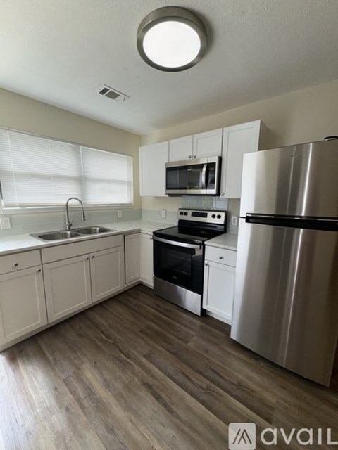 A kitchen with white cabinets and a stainless steel refrigerator.
