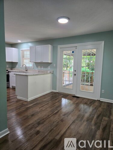A kitchen with white cabinets and a wooden floor.