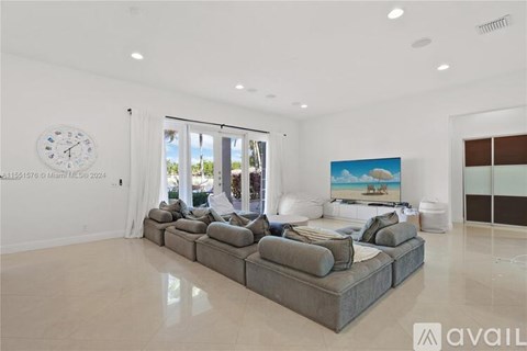 A living room with a large grey sofa and a painting of a beach scene on the wall.