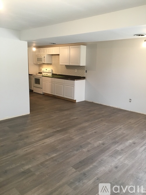 A kitchen with white cabinets and a wooden floor.