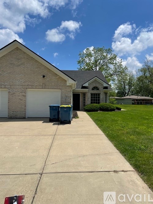 A house with a driveway and two bins in front.