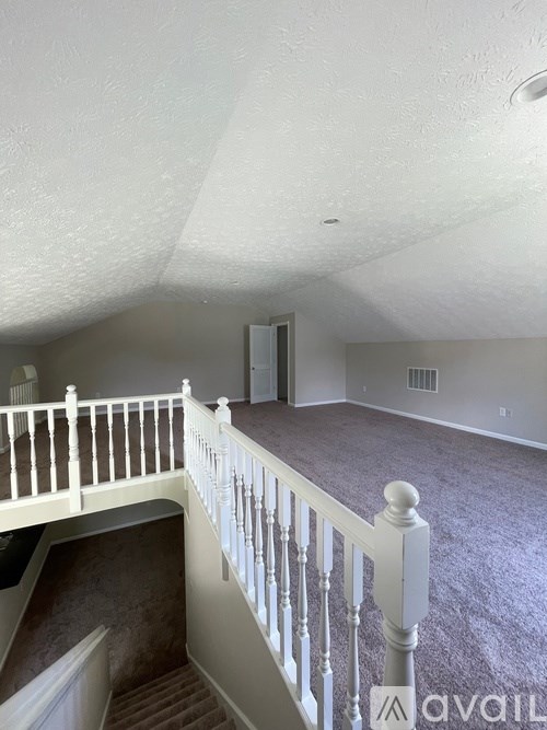 A white railing leads to a second floor bedroom.