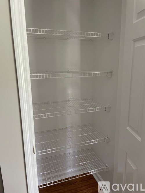 Empty white shelves in a white fridge.