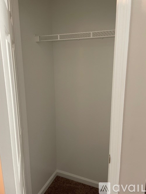 A white closet with a shelf and a door.