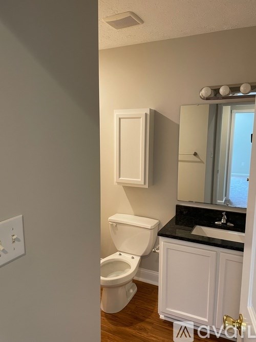 A white toilet sits in a bathroom next to a sink.