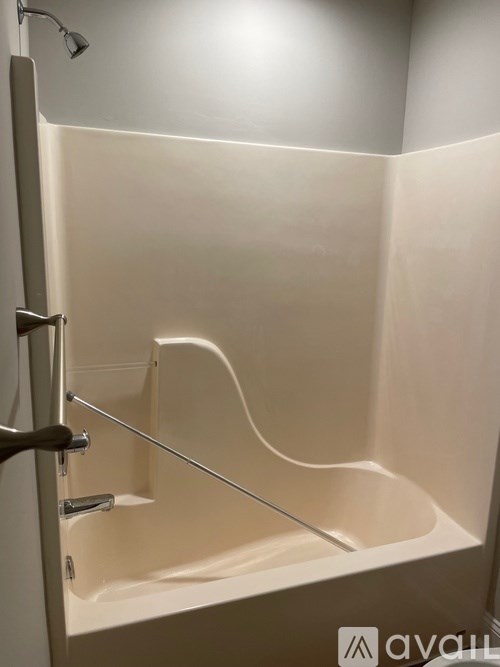 A white bathtub with a shower head and a glass door.