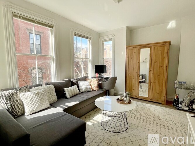 A living room with a grey couch, a white coffee table, and a wooden cabinet.