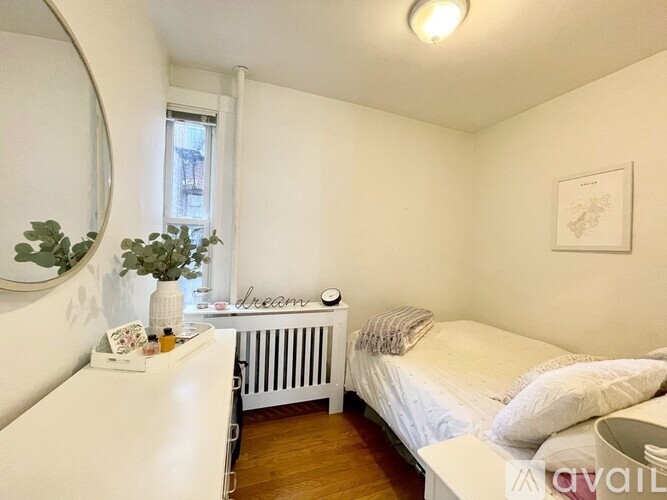 A bedroom with a bed, nightstand, and a window with a view of a building outside.