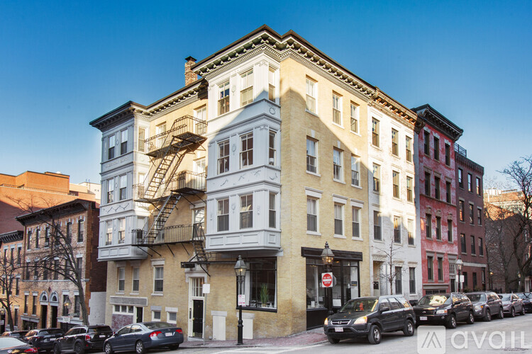 A row of buildings with cars parked in front.