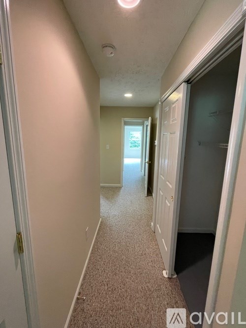 A long hallway with a carpeted floor and white walls.
