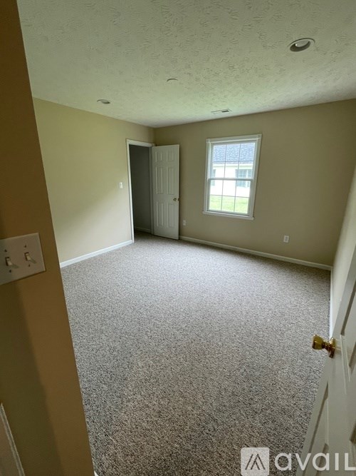 A carpeted room with a door and a window.