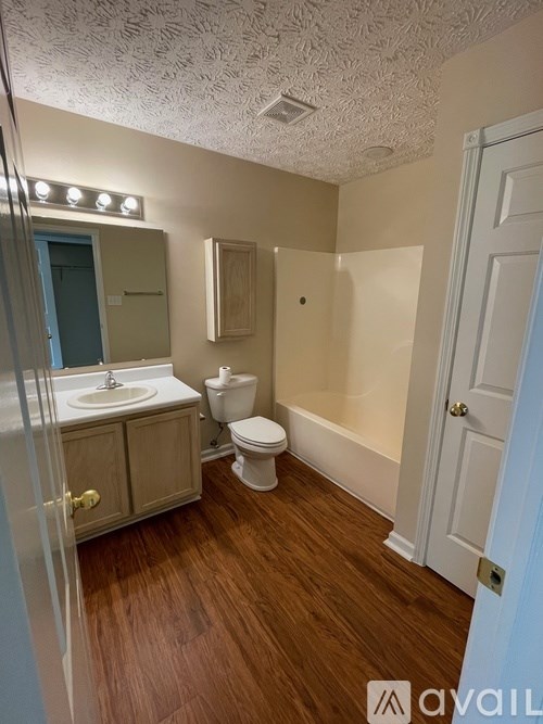 A bathroom with a toilet, sink, and mirror.