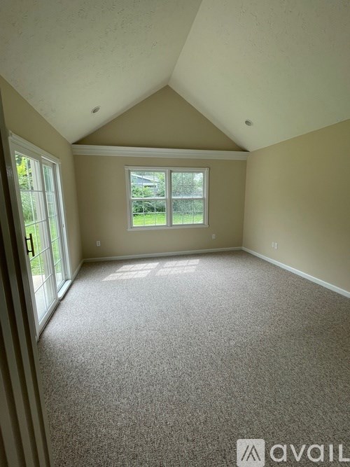 A room with a carpeted floor and a window letting in sunlight.